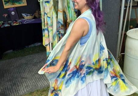 Woman twirling in a colorful, flowing outfit at an outdoor event.